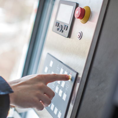 A hand operates the keypad of the DOLL OCS operating and control system